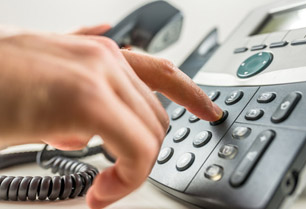 Ein Mitarbeiter wählt eine Telefonnummer im Büro telefonanlagen.jpg